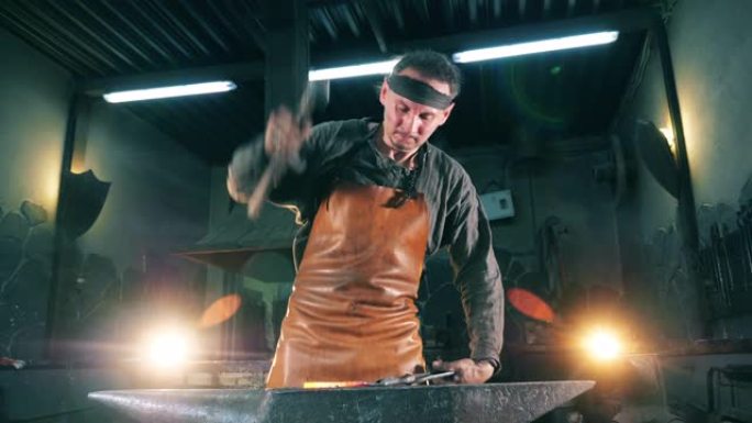 一个铁匠在锻炉上用刀工作时使用锤子。