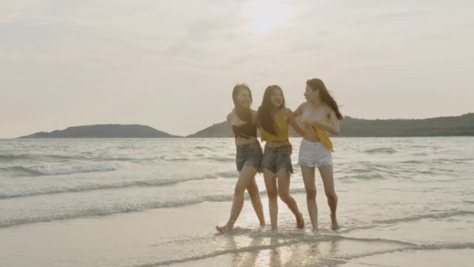 一群亚洲年轻女性在海滩上散步，朋友们快乐放松，晚上日落时在海边的海滩上玩耍。生活方式朋友旅行假期假期