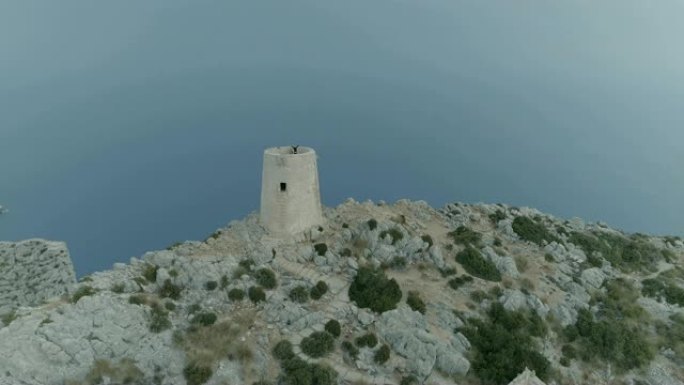 女人张开双臂在马略卡岛的塔楼欣赏风景。