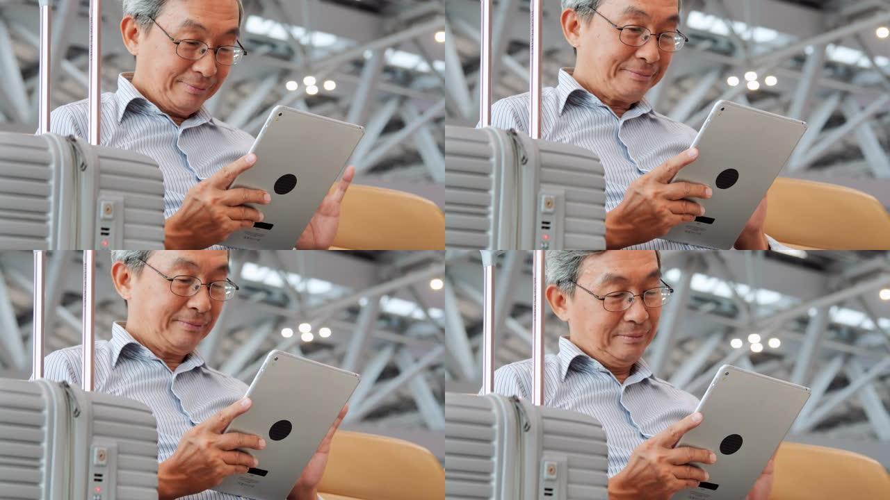 亚洲老人看着他的实验室屏幕微笑。他坐在机场。旅行，旅行，全球，生活方式，假期，技术概念。在机场