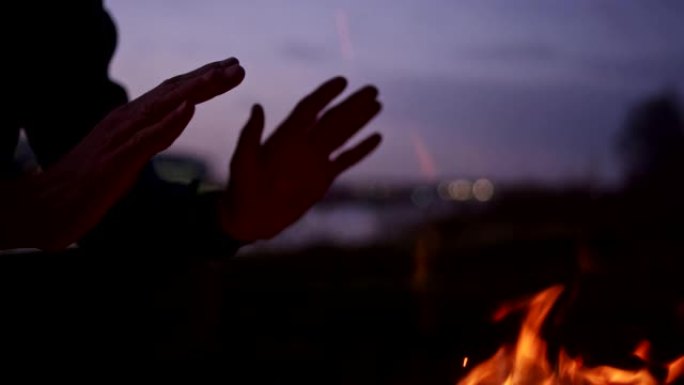 孤独的人在河边燃烧篝火。热身手