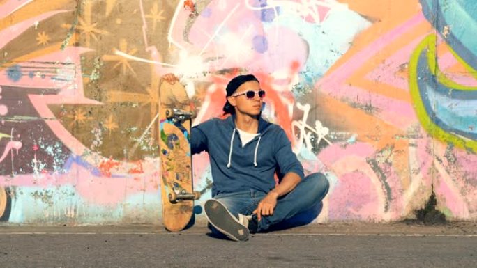 男性少年正坐在滑板涂鸦墙附近