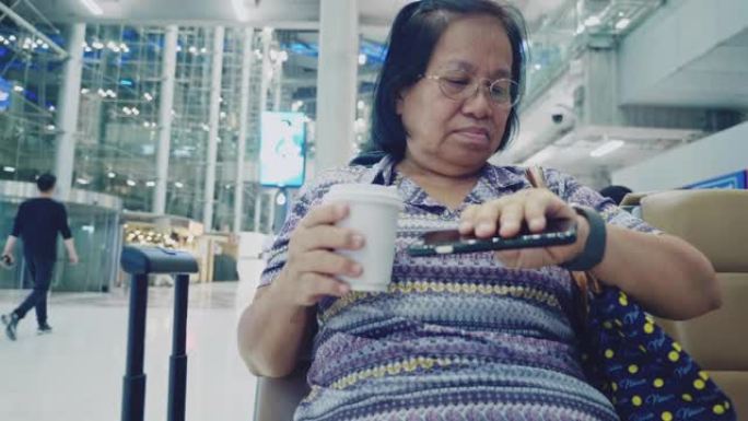 亚洲资深女性在机场使用智能手机
