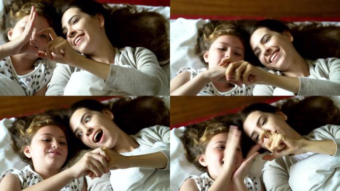 母亲在舒适的氛围中与女儿在床上玩耍，传递母亲对女儿的温暖，母女长发金发