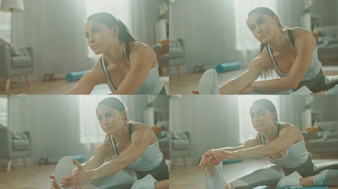 一个美丽自信的健身女孩在她明亮宽敞的客厅和舒适简约的室内做伸展瑜伽练习，穿着运动运动服。