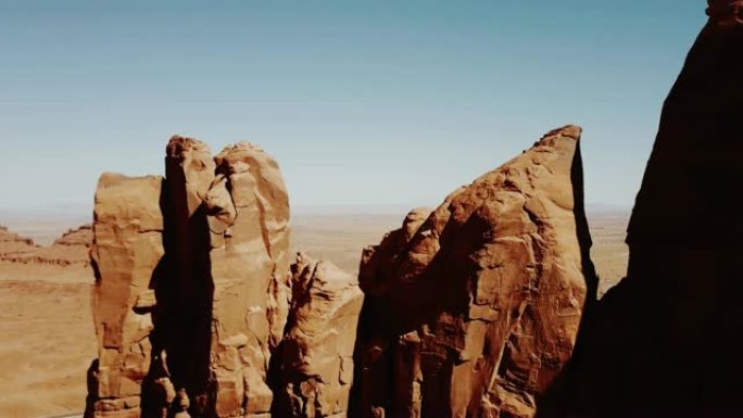 在阳光明媚的日子里，无人机接近美国亚利桑那州纪念碑谷干燥沙漠中令人惊叹的岩石悬崖结构。