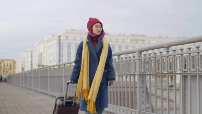女游客带着行李在城市桥上行走