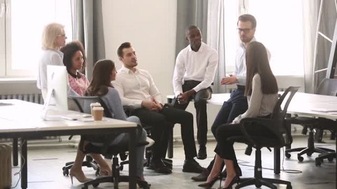 男性公司团队负责人在会议上教授多元化的工人小组