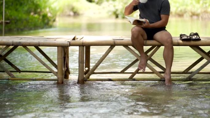 一个男人放松看书，在桥上喝咖啡