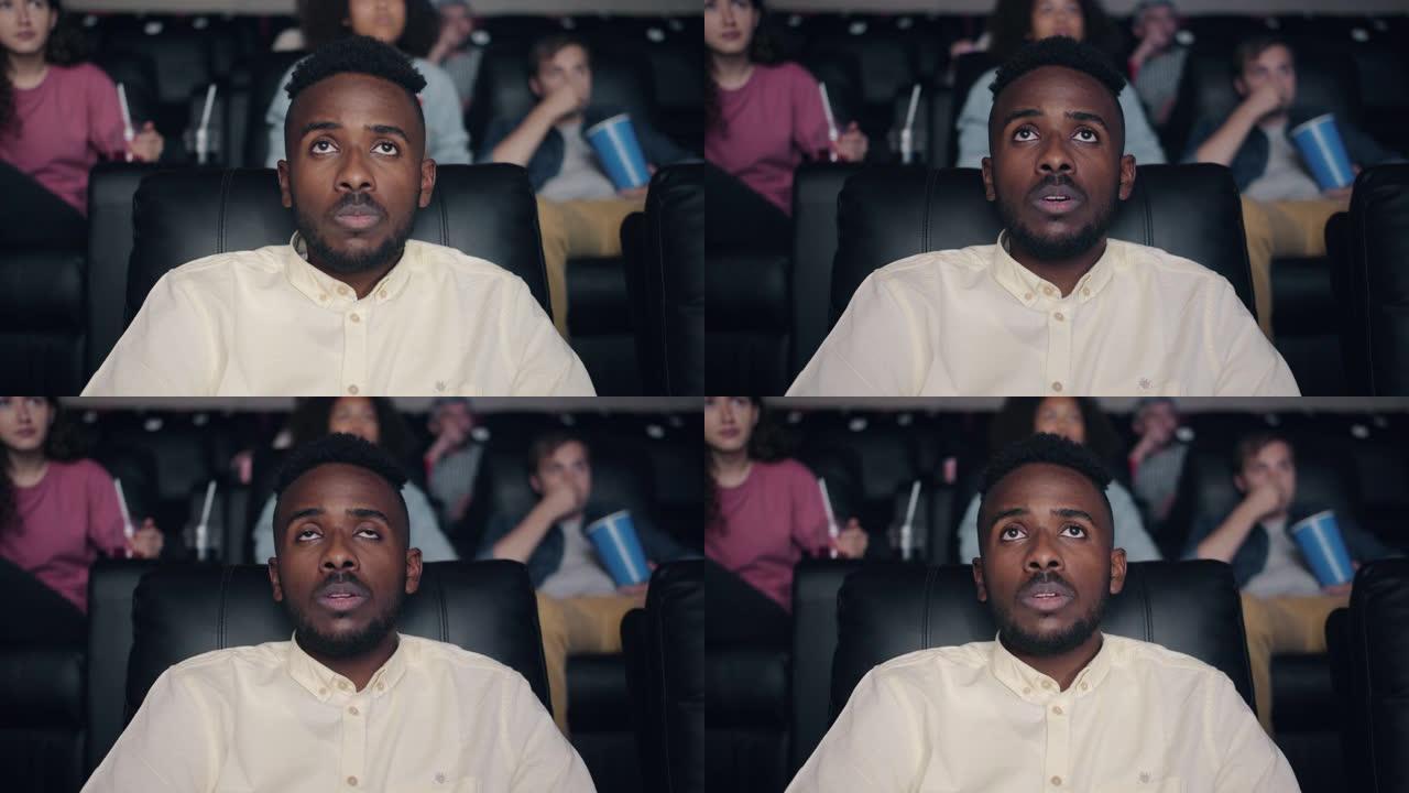 悲伤和疲惫的非洲裔美国人在电影院看电影独自放松