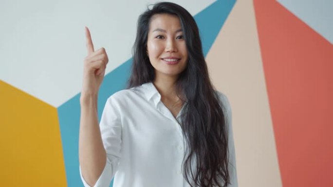 创意亚洲女性举起手指的肖像有好主意感到快乐