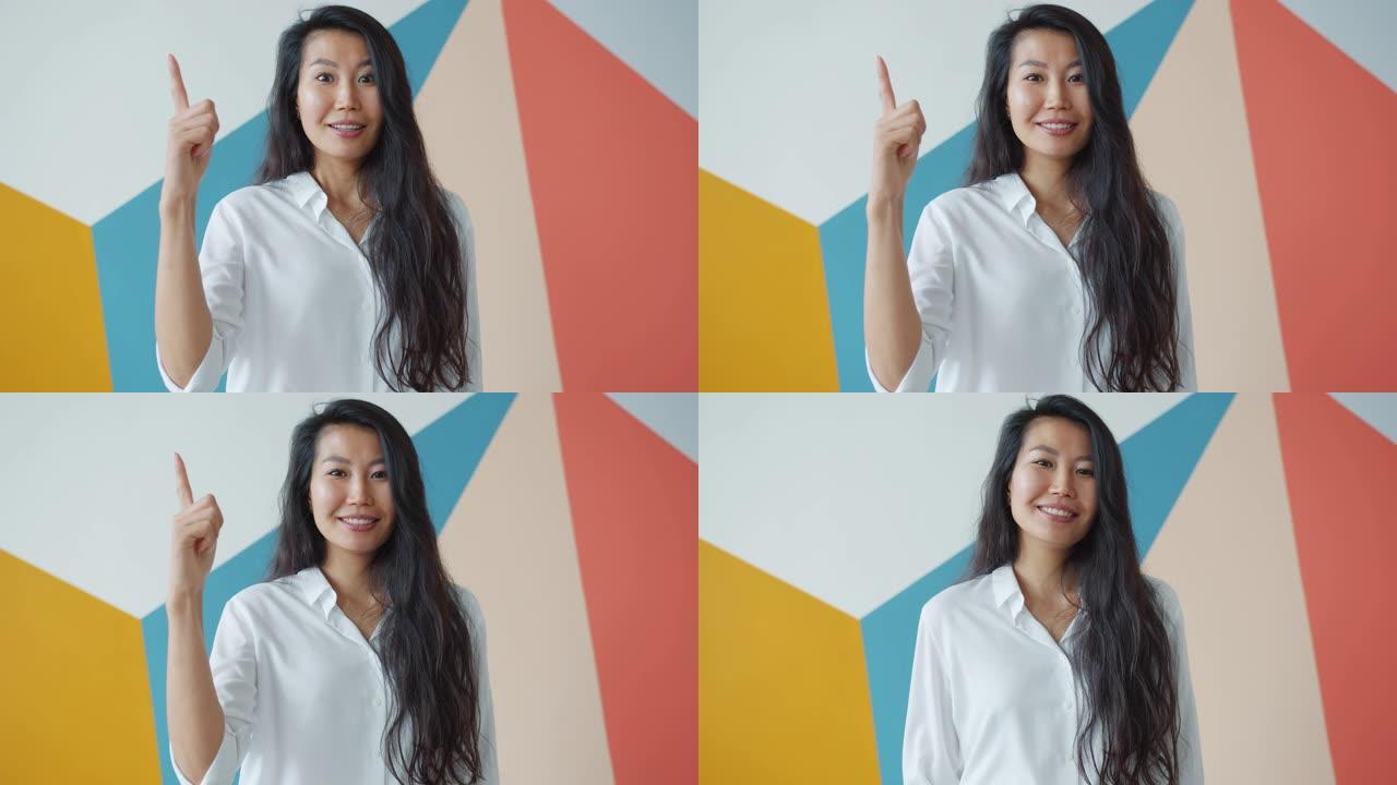 创意亚洲女性举起手指的肖像有好主意感到快乐
