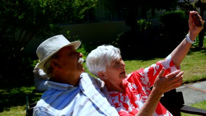 活跃的高加索高级夫妇在努尔辛花园用手机自拍的前视图