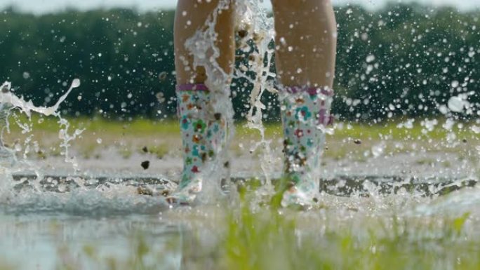 穿着橡胶靴的SLO MO时间翘曲效果女人溅在泥泞的水坑里