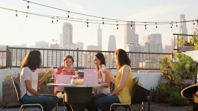 女性朋友在屋顶露台庆祝生日，背景是城市天际线