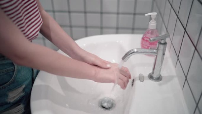 亚洲妇女在厕所，洗手间里用消毒肥皂仔细洗手。