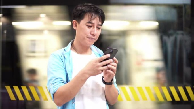 亚洲男子在地铁站使用手机