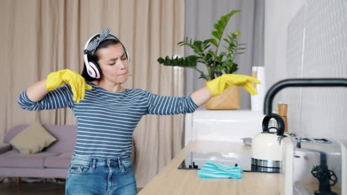 戴着耳机的女孩唱歌跳舞，然后戴着橡胶手套打扫厨房