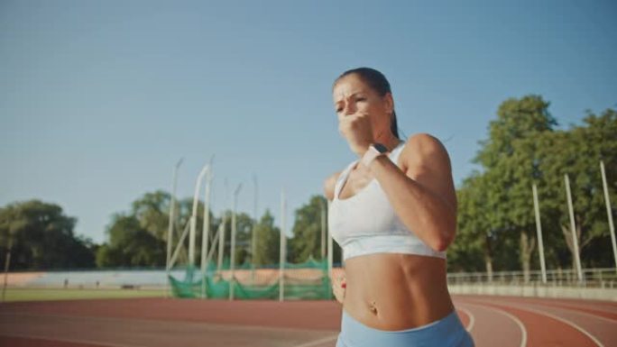 在体育场慢跑的浅蓝色运动上衣中，一位美丽的健身女子的特写肖像照片。她在一个温暖的夏日跑步。运动员在赛