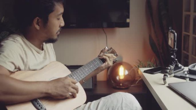 亚洲男子在家中学习弹吉他