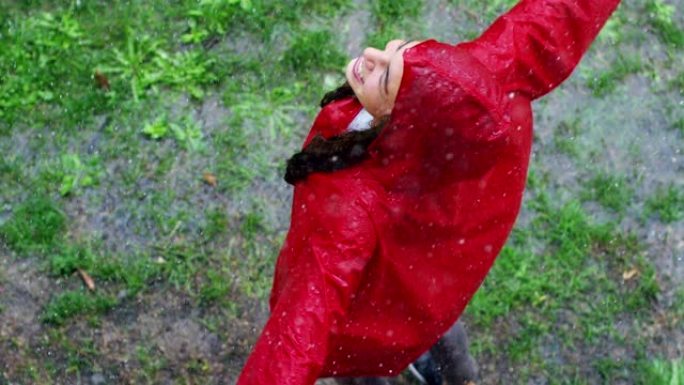 一个快乐的女人在雨中微笑，女人沉浸在快乐自由的雨中慢动作下的舞蹈中。