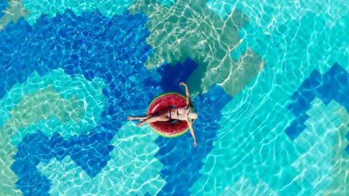 一个女孩在旅馆的游泳池里坐在橡胶圈上。