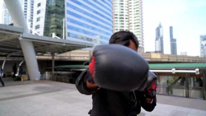 商人用拳击手套拳击。商业竞争的概念。以城市景观为背景的户外拳击手套商人的前视图。