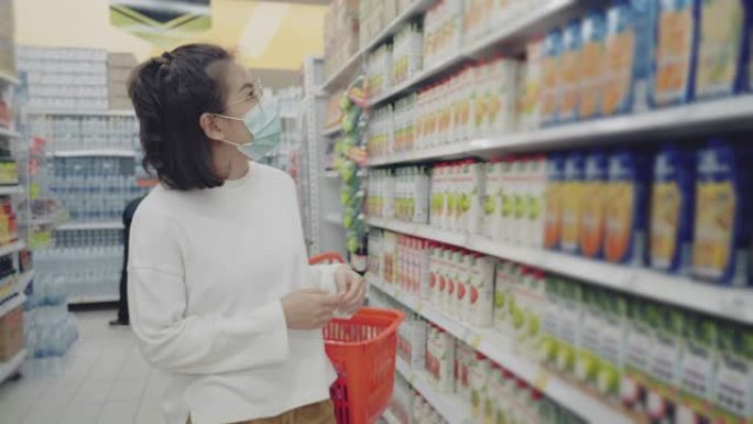 戴着防护口罩的年轻女孩在超市购物。