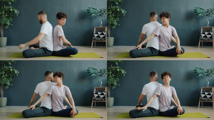 在健康中心坐在一起享受双人瑜伽的女孩和男孩的慢动作