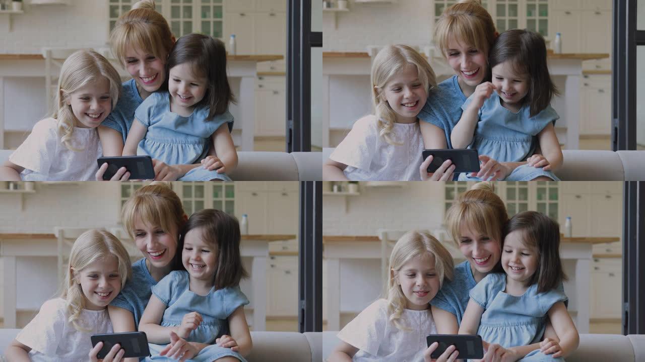 快乐的母亲和小女儿笑着在智能手机上看动画片