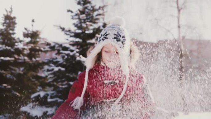 穿着冬装的快乐可爱的欧洲小女孩向空中扔雪，看着相机，微笑着慢动作。