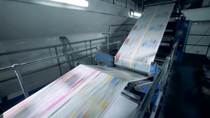 彩色报纸在印刷传送带上移动，现代技术。
