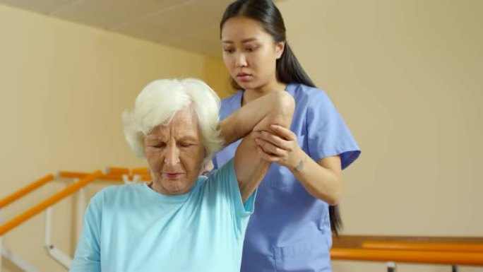 老年患者的女理疗师伸展手臂
