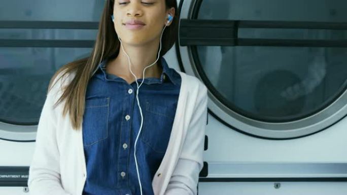 女人在自助洗衣店4k手机上听音乐