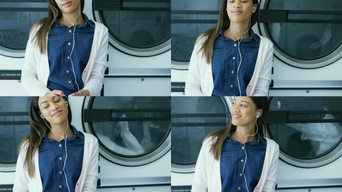 女人在自助洗衣店4k手机上听音乐