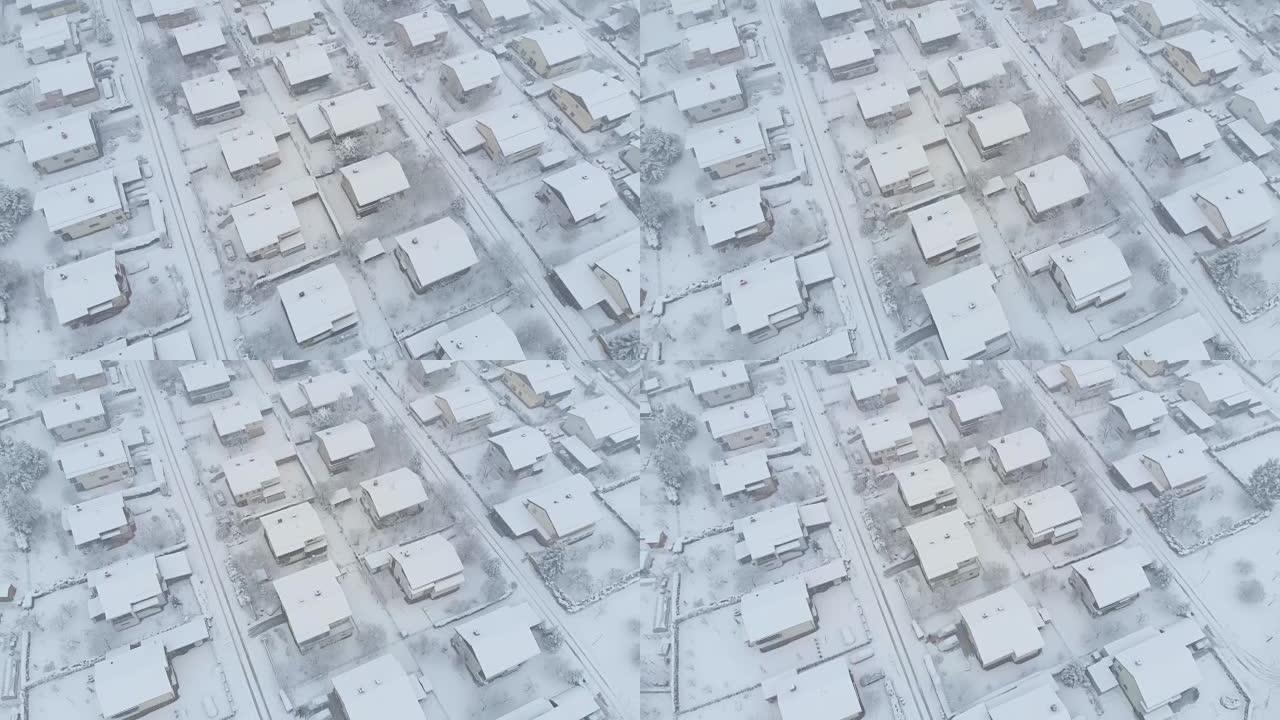 空中: 在郊区白雪皑皑的屋顶和街道上飞行。