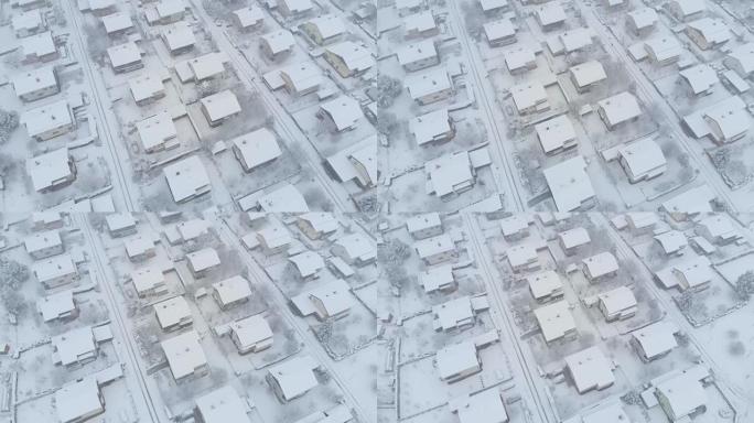 空中: 在郊区白雪皑皑的屋顶和街道上飞行。