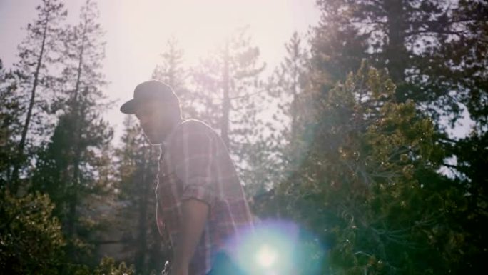 镜头跟随年轻快乐的当地男子穿着方格衬衫独自在美丽的优胜美地国家森林慢动作徒步旅行。