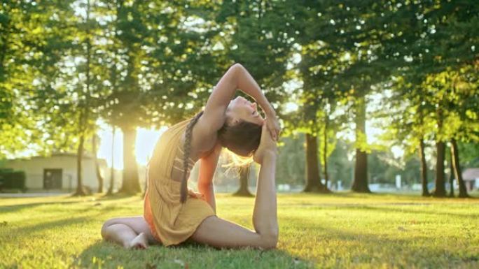 优雅，灵活的年轻女子在阳光明媚的公园练习瑜伽