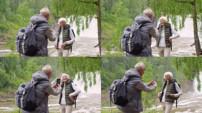 高级男子在远足时为老妇拍照