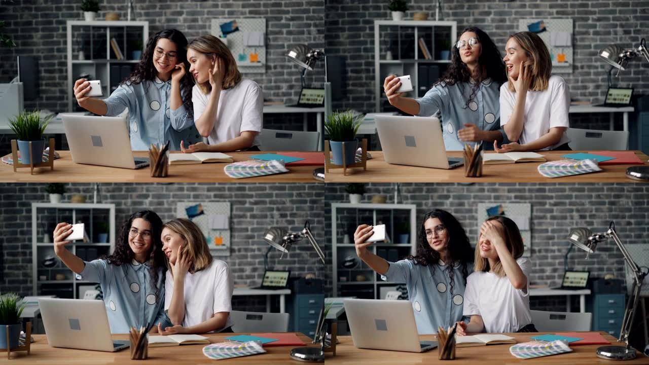 美丽的年轻女性伴侣在办公室使用智能手机相机自拍
