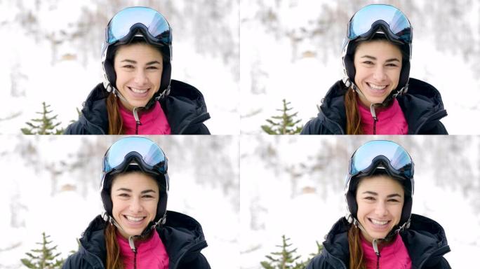 一个微笑的滑雪者在山上度假的肖像，在她身后你可以看到白雪覆盖的山。