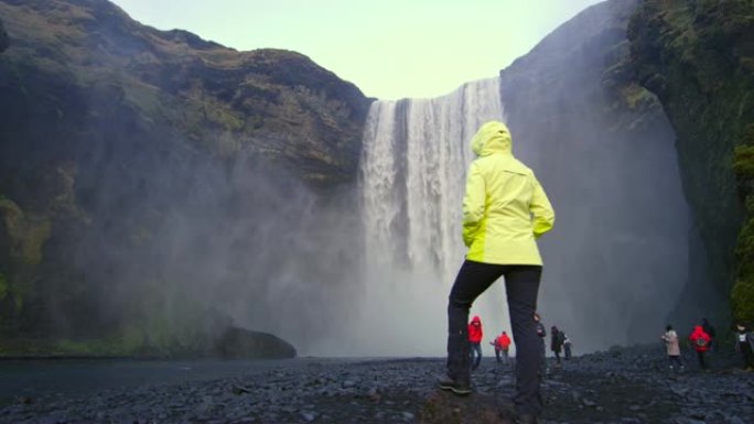 女士站在冰岛Skogafoss瀑布下