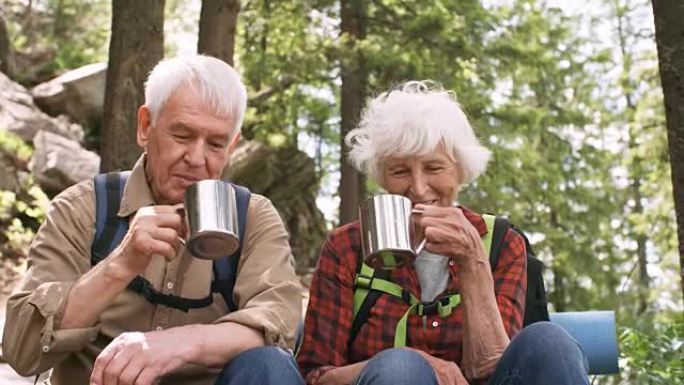 高级夫妇在森林徒步旅行时喝茶