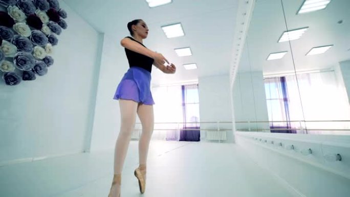 一个女孩在芭蕾舞课上跳，侧视图。
