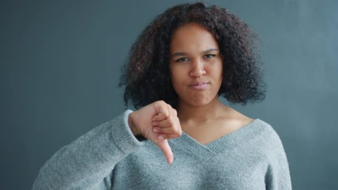 美丽的非裔美国女孩的肖像表现出拇指朝下的手势