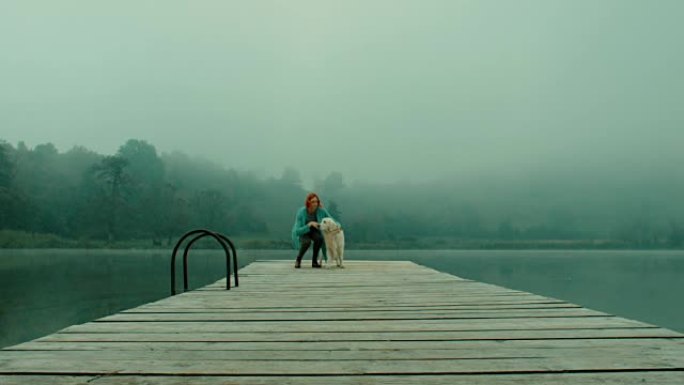 女人和狗在湖边的码头上散步