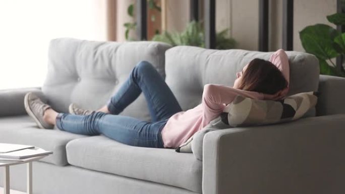 放松的年轻女子躺在沙发上享受白天的午睡