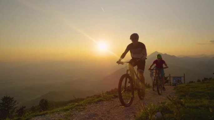 低角度: 傍晚的阳光照耀着骑着自行车上坡的旅行者。