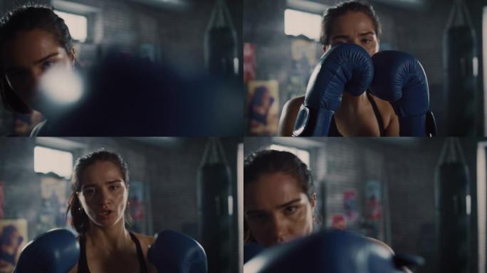 一位美丽健康的黑发跆拳道运动员在镜头前摆姿势，双手戴着蓝色战斗手套。女孩在镜头前挥拳。她在地下健身房